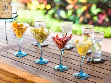 Colourful fruit cocktails sit on an outdoor table.