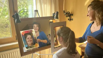 Zwei Personen lächeln im Raum mit Spiegel.