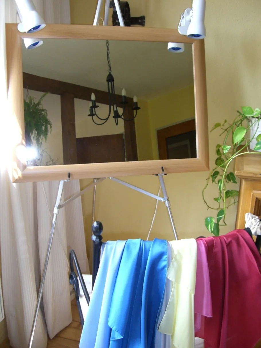 Easel with mirror, draped fabrics, indoor room.