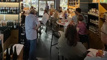 Personen essen in gemütlicher Weinladen-Umgebung.