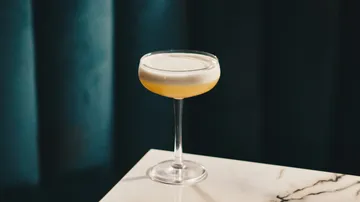 Cocktailglas auf Marmortisch, dunkler Hintergrund.