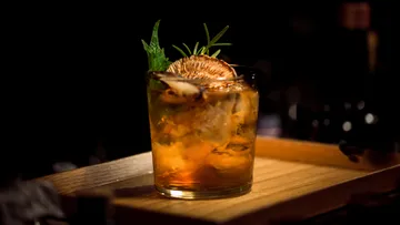 Cocktail garnished with herbs and dried citrus.