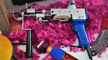 Tufting-Pistole auf Tisch mit pinker Wolle.