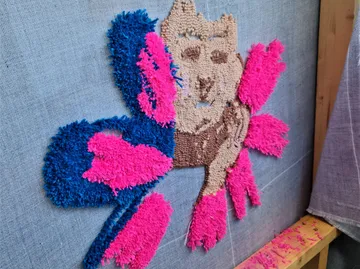 Bunte tuftierte Textilkunst auf Leinwand.