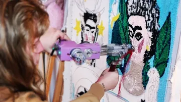 Person benutzt Tufting-Pistole auf buntem Kunstwerk.