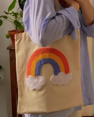 Person mit Stofftasche mit Regenbogendesign.