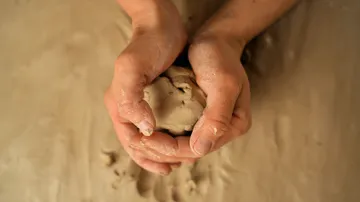 Hands shaping clay in a studio.