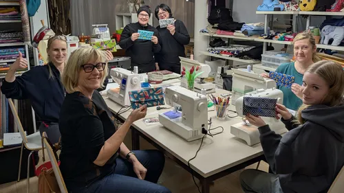 Group sewing at table with machines.