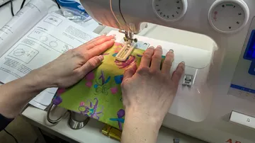 Hands sewing fabric on a machine.