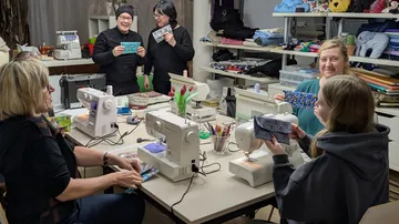 Women sewing and chatting in a workshop.