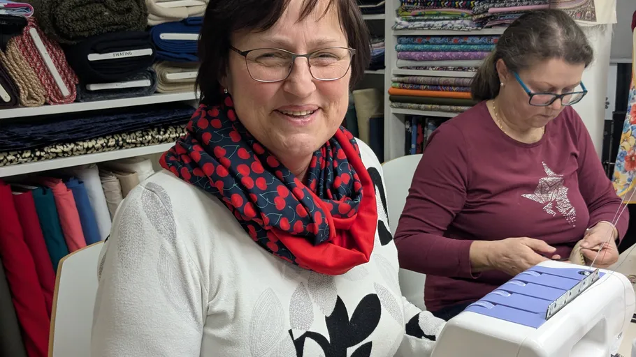 Two women sewing in a fabric store.