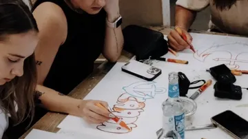 Group drawing on white paper with markers.