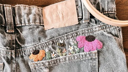 Blumenstickerei auf Jeans-Tasche.
