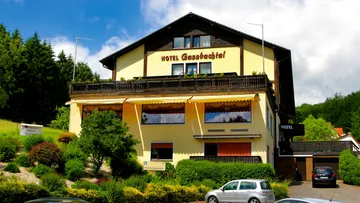 Hotel building surrounded by trees and cars.