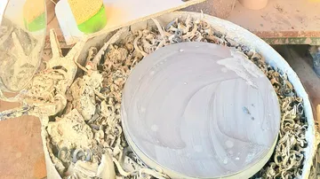 Pottery wheel with clay trimmings, studio setting.