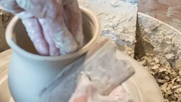 Hands shaping clay on a pottery wheel.