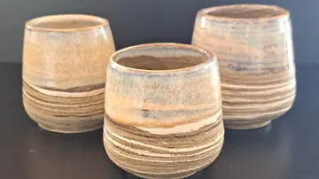 Drei gestreifte Keramikbecher auf einem Tisch.