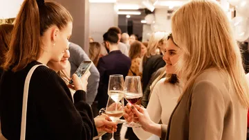 Frauen stoßen mit Weingläsern auf einer Party an.