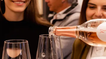 Rosé wine poured into glasses, people smiling.