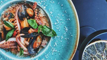 Seafood and pasta dish on blue plate.
