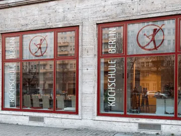 Fenster der Kochschule Berlin shows logo and name.