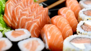 Verschiedene Lachs-Sushi auf einem schwarzen Teller.