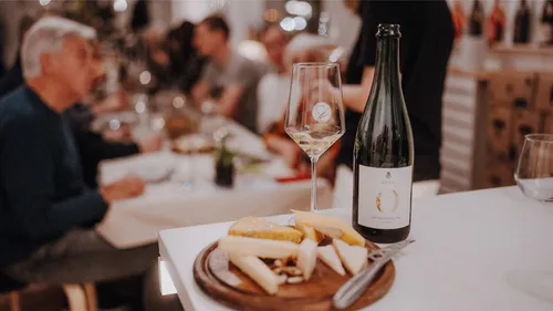 Wine and cheese on table, people dining.