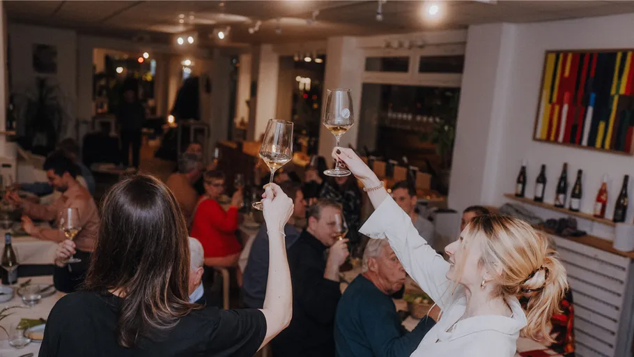 Zwei Frauen stoßen in einem lebhaften Restaurant an.