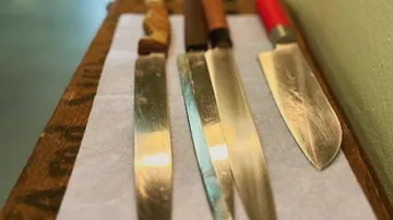 Vier Messer auf einer Holzoberfläche arrangiert.