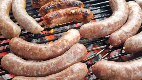 Würste grillen über heißen Kohlen auf Grill.