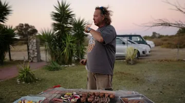 Mann grillt Fleisch im Garten.
