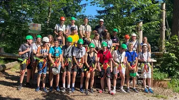 Group wearing helmets and harnesses in a forest.