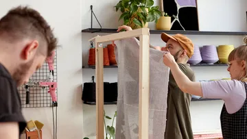 People assembling a weaving loom in a studio.