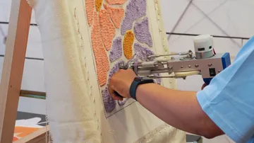 Person benutzt Tuftpistole auf Stoffkunstwerk.