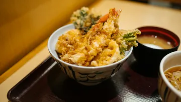 Tempura rice bowl on a tray, indoors.