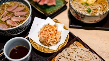 Japanese dishes with noodles and tempura on table.