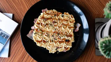 Okonomiyaki-Pfannkuchen auf schwarzem Teller.