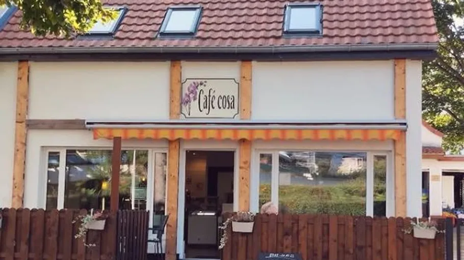 Vorderansicht eines Cafés mit Außensitzplätzen.
