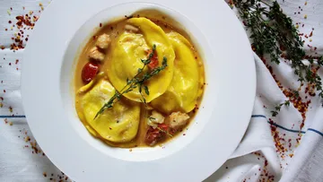 Ravioli in Soße auf weißem Teller.