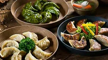 Assorted dumplings on plates with garnish.