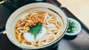Udon noodles with mushrooms and leaf garnish.