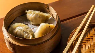 Dumplings in einem Bambusdämpfer auf einem Tisch.