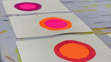 Three abstract paintings on a table.