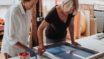 Two women screen printing in a workshop.
