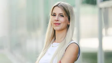 Woman smiling, outdoors, blurred background.
