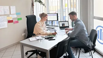 Two people discussing at an office table.