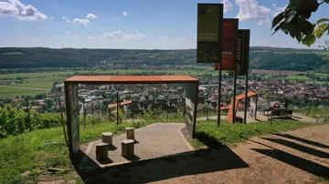 Aussichtspunkt mit Bänken über Dorflandschaft.