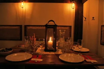 Kerzenbeleuchteter Tisch mit Tellern in dunklem Raum.