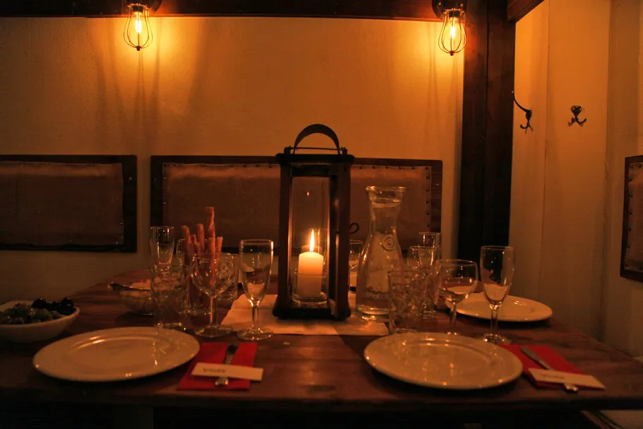 Candlelit table with plates in dimly lit room.