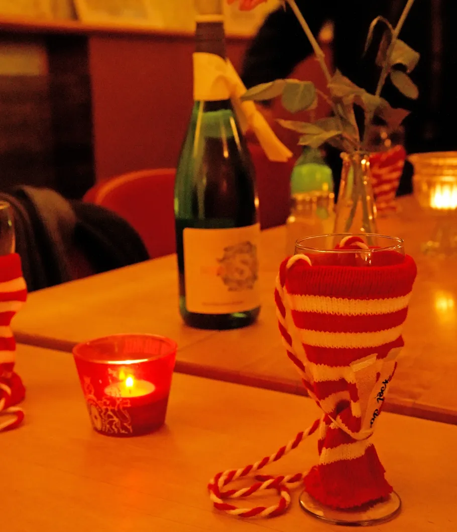 Glass with sock, candle, wine bottle on table.